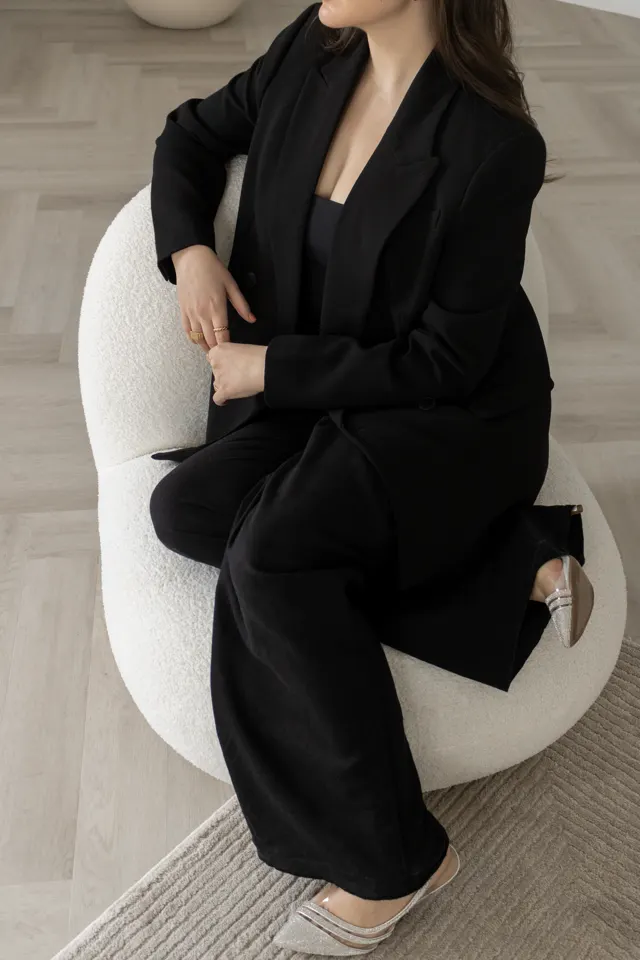 Mulher de blazer preto sentada em uma poltrona