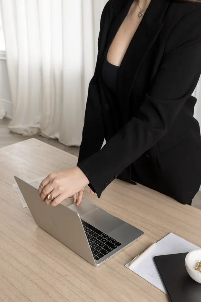 Mulher de blazer preto trabalhando no notebook