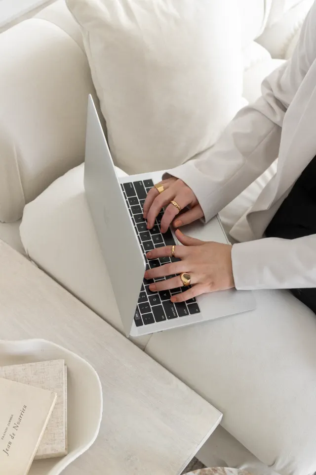 Mãos no teclado de um notebook sobre o colo