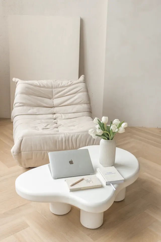 Sala com sofá e mesa com flores e notebook